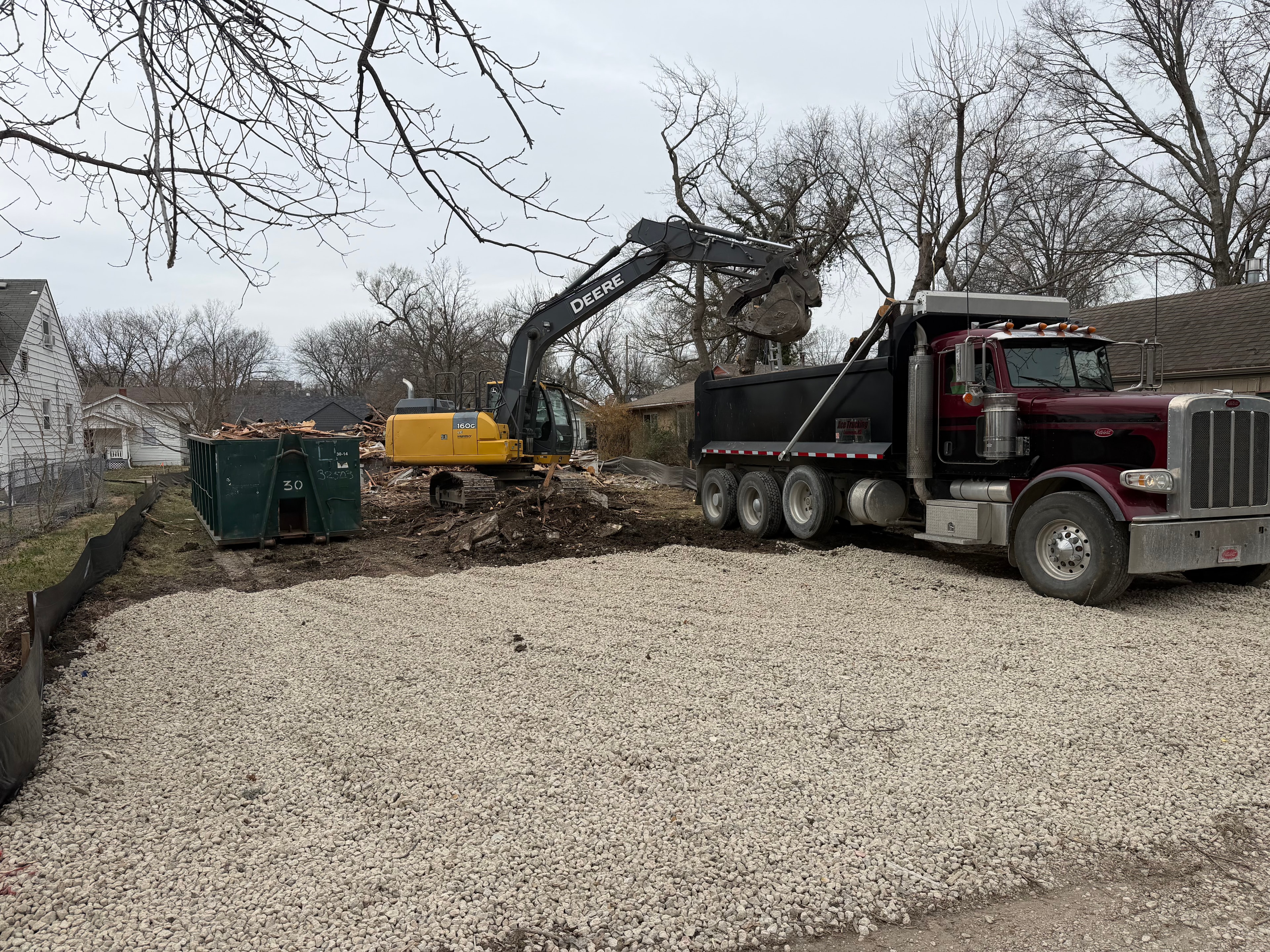 Excavator loading debris into a dump truck during site clearing