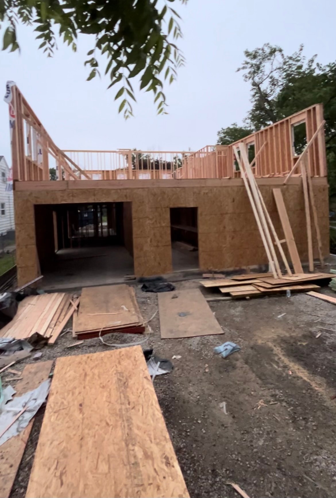 First floor sheathed in OSB with second floor framing rising and window openings cut in